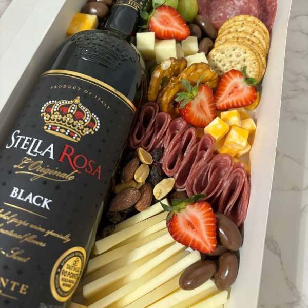 Gift box with a wine bottle, crackers, cheese, fruit, nuts, and sliced meats