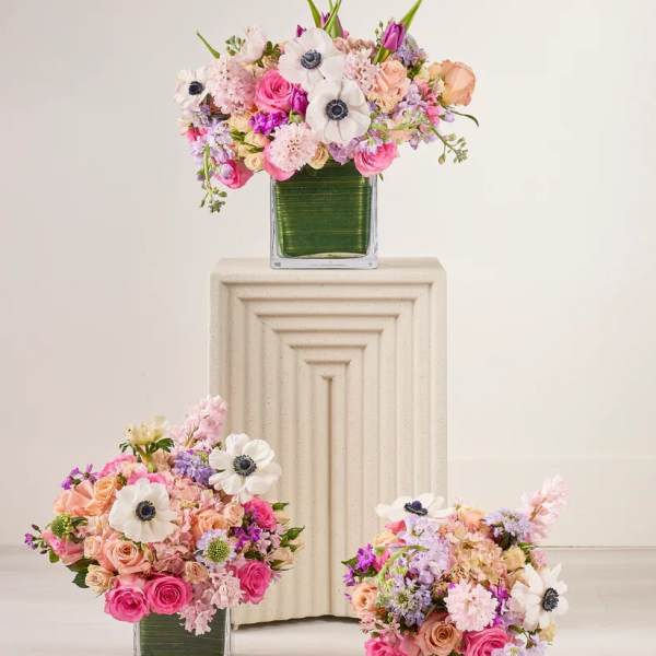 Three pastel floral arrangements in square glass vases
