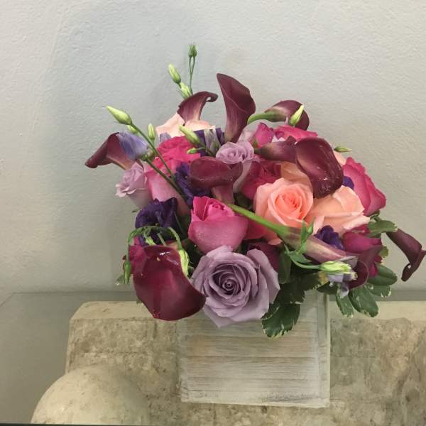 Bouquet of roses and calla lilies in pink, purple, and burgundy tones