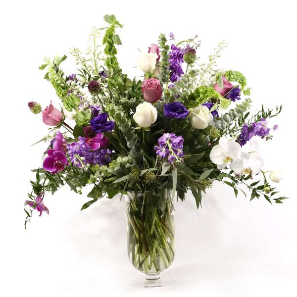 Mixed purple, pink, and white flowers in a clear glass vase