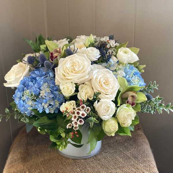 White roses and blue hydrangeas in a round vase