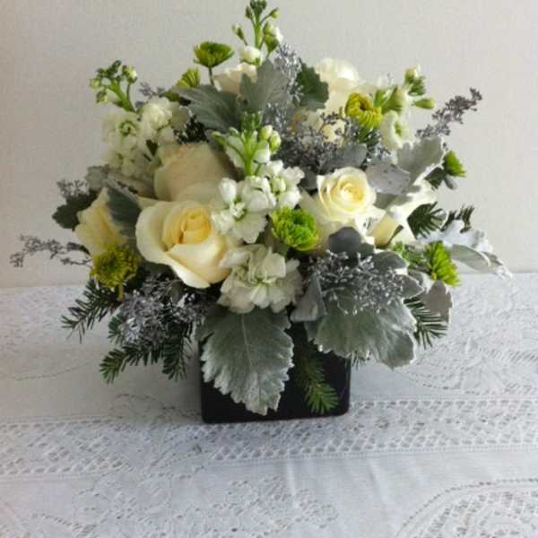 White roses and green-white flowers in a black square vase