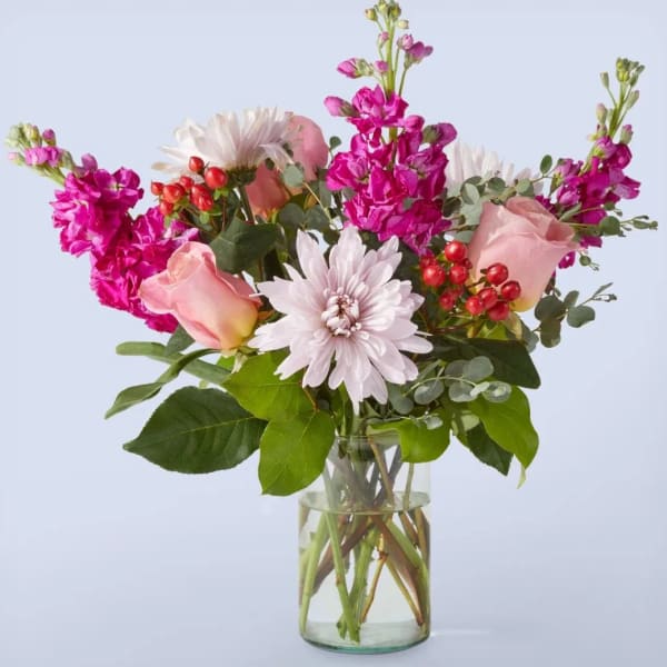 Pink roses, white mums, and bright magenta flowers in a clear glass vase