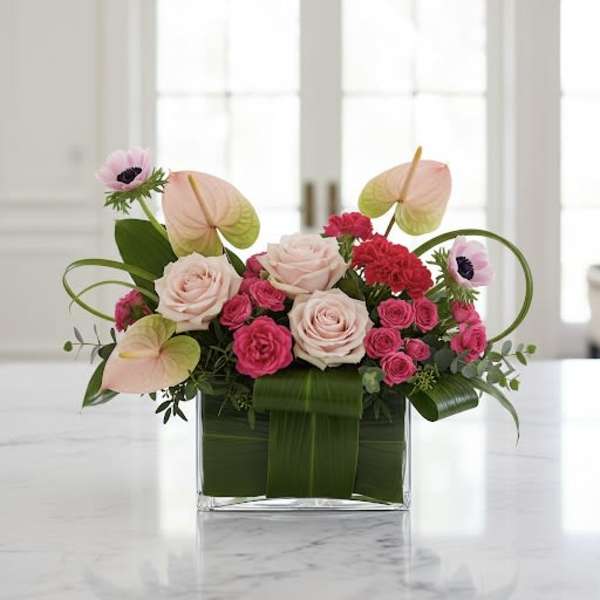 Pink roses and anthuriums in a square glass vase
