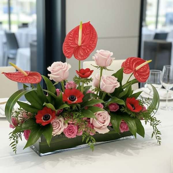 Pink roses and red anthuriums in a rectangular glass vase
