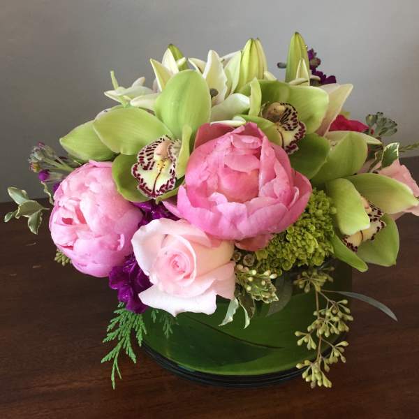 Pink peonies and roses with green orchids in a low vase