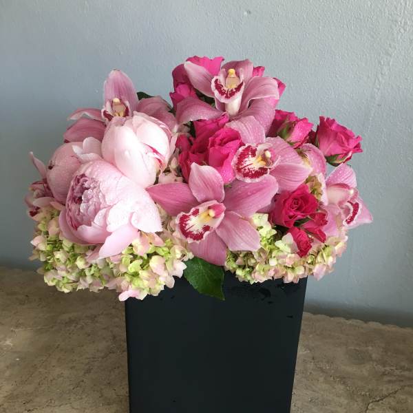 Pink orchid and rose arrangement in a black rectangular vase