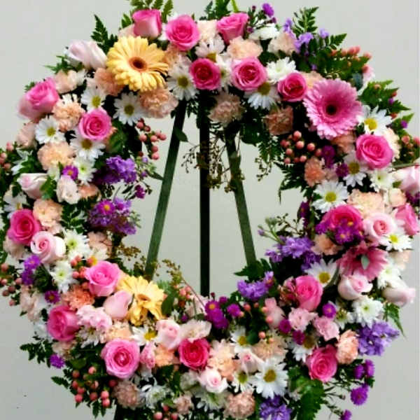 Large floral wreath with pink roses, daisies, and purple flowers