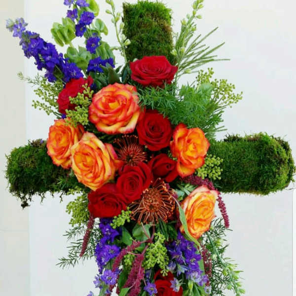 Cross-shaped floral arrangement with red and orange roses and purple flowers