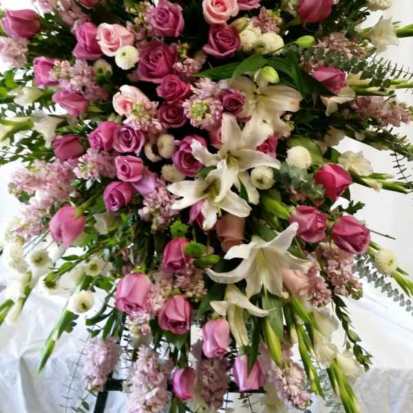 Large standing spray of pink roses, white lilies, and pale filler flowers