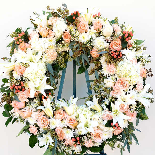 Large floral wreath with white lilies, peach roses, and pink berries