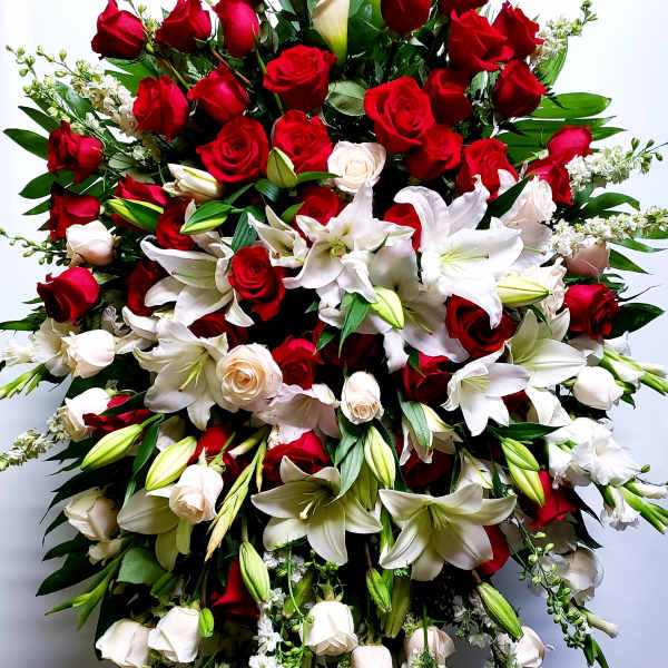 Large standing spray of red roses and white lilies with trailing white flowers