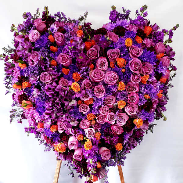 Large heart-shaped floral arrangement of purple, pink, and orange roses