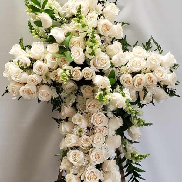 Large white rose cross arrangement on a wooden stand