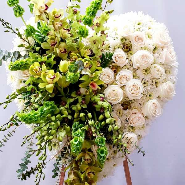 Large floral standing spray with white roses and green orchids on an easel