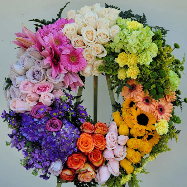 Heart-shaped floral wreath with multicolored roses, gerbera daisies, hydrangeas, and carnations