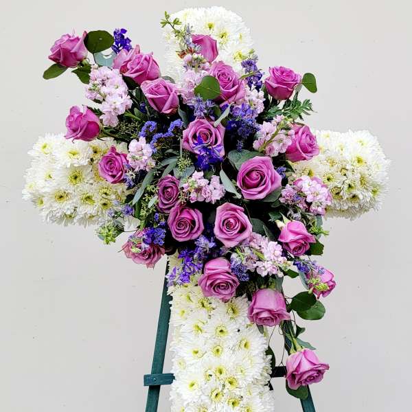 Cross-shaped floral spray with pink roses and white chrysanthemums on an easel