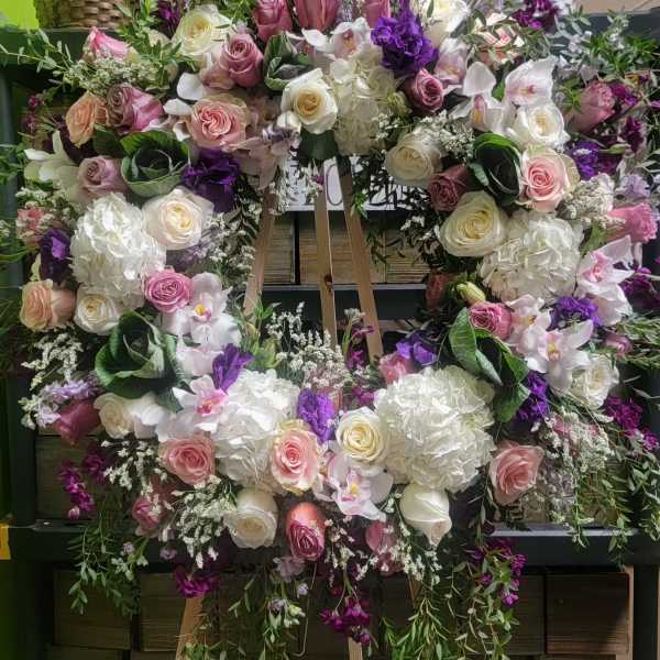Large floral wreath with pink, white, and purple flowers on an easel