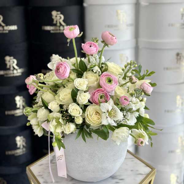 Pink and white flowers arranged in a round gray vase