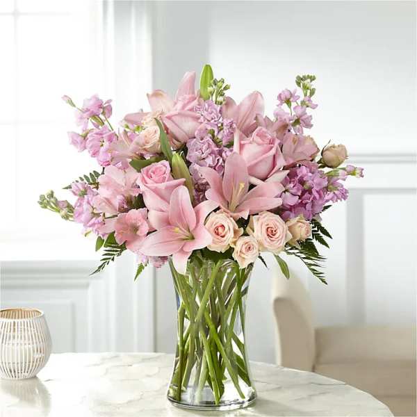 Pink lilies and roses arranged in a clear glass vase