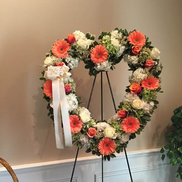 Heart-shaped floral wreath on a stand with pink and white flowers