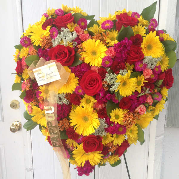 Heart-shaped bouquet of red roses and yellow daisies on a stand