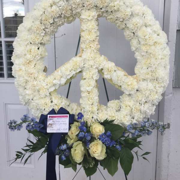 White floral peace sign standing spray with blue and cream flowers at the base