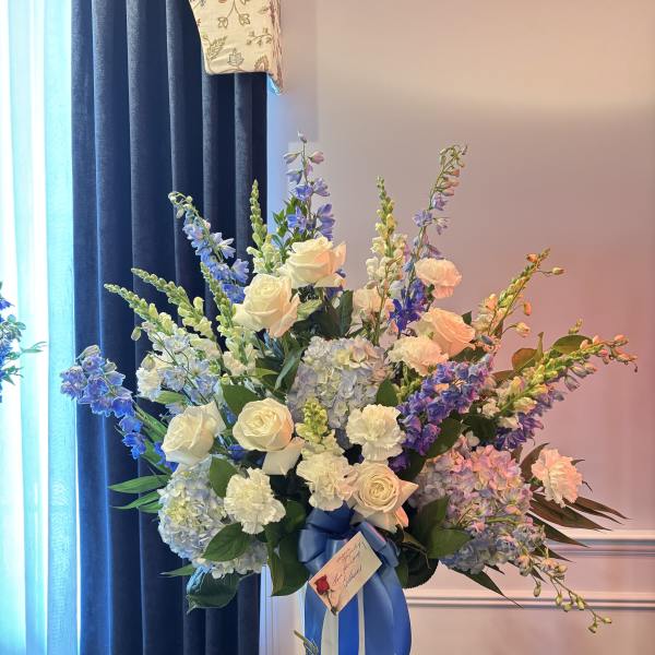 Large bouquet of white roses, blue flowers, and hydrangeas in a white vase