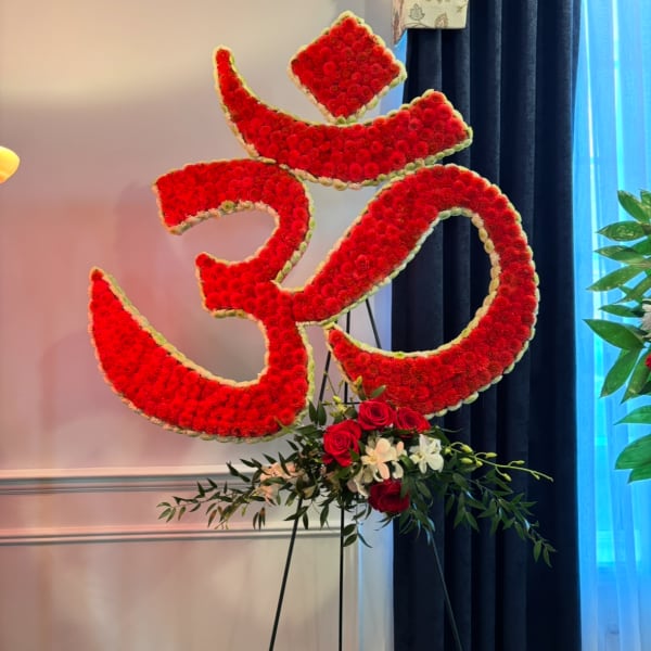 Large red floral Om symbol on a stand with roses at the base