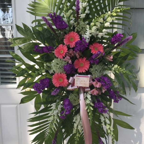 Large standing floral spray with pink gerbera daisies and purple flowers