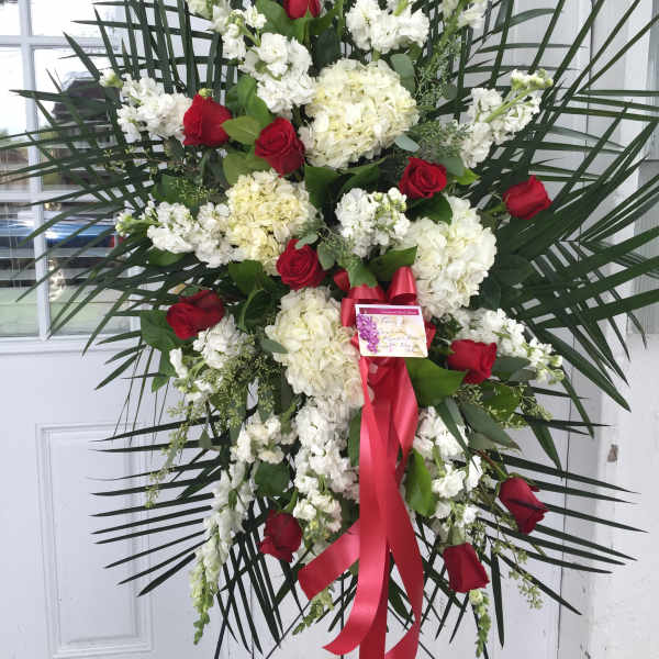 Standing floral spray with red roses, white blooms, and a red ribbon