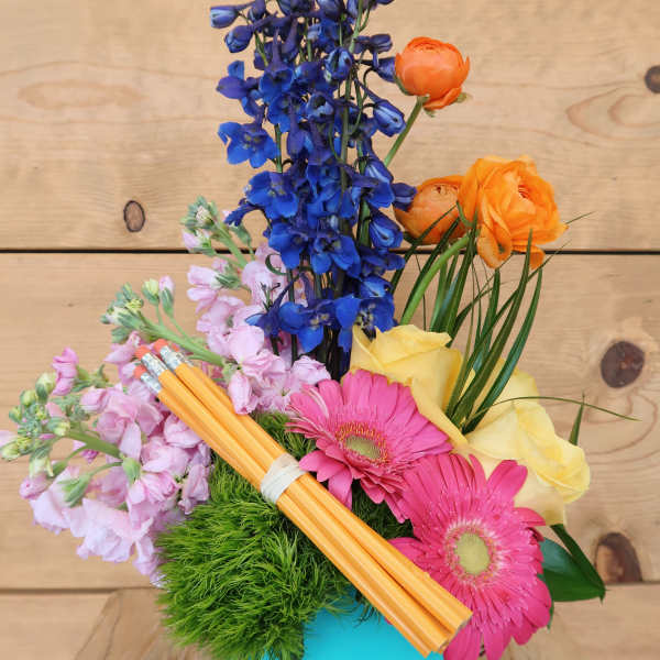 Colorful bouquet in a turquoise vase with blue, pink, yellow, and orange flowers