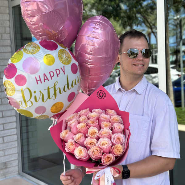 Man holding pink rose bouquet and birthday balloons