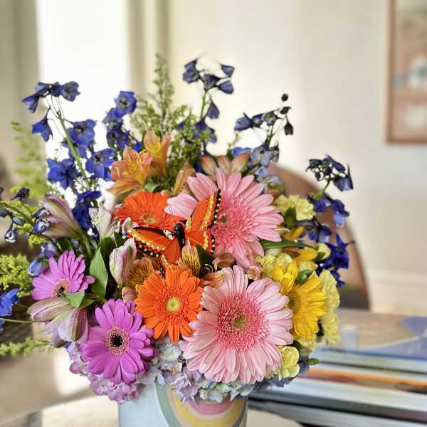 Colorful mixed bouquet in a pastel vase with a butterfly decoration