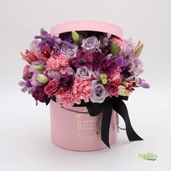 Pink hatbox arrangement with purple and pink flowers and a black ribbon
