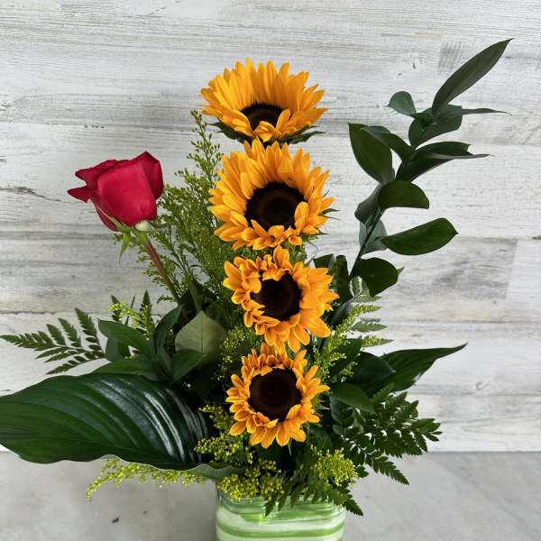 Sunflowers and a red rose in a striped glass vase