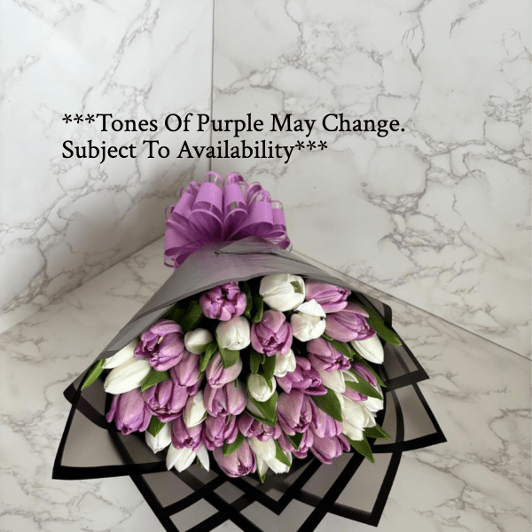 Bouquet of purple and white tulips wrapped in black paper with a purple bow