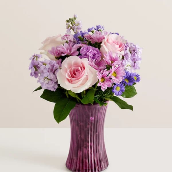 Pink and lavender flower bouquet in a purple glass vase