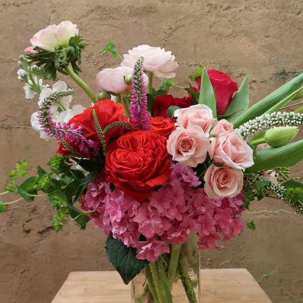 Mixed bouquet of red, pink, and white flowers in a glass vase