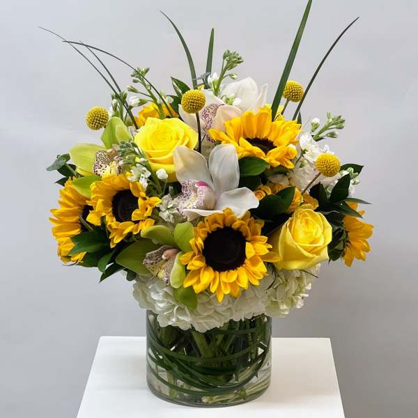 Yellow sunflowers and roses in a glass vase with white orchids