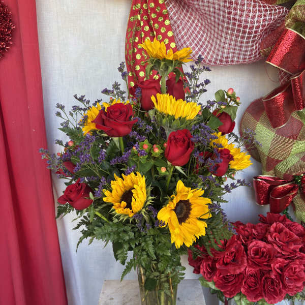 Bouquet of red roses and yellow sunflowers in a glass vase