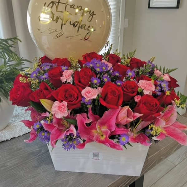 Red roses and pink lilies in a white box with a birthday balloon