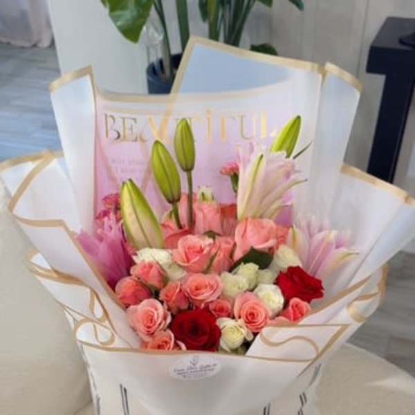 Pink and red rose bouquet with lily buds in white wrap