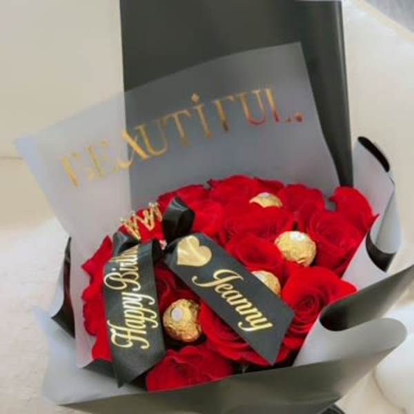 Bouquet of red roses with gold-wrapped chocolates and a black ribbon