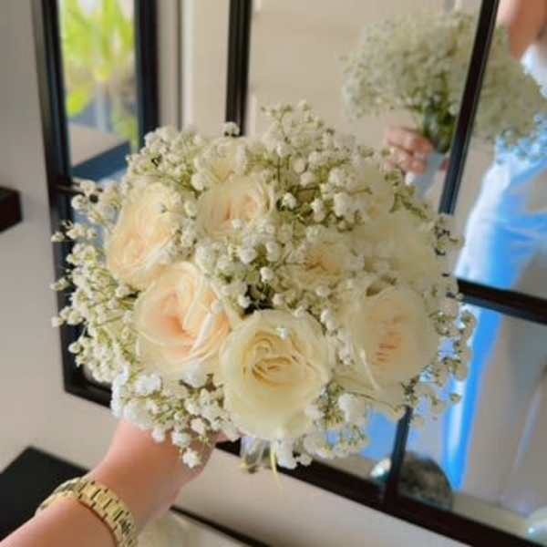 Cream rose bouquet with baby's breath held in hand