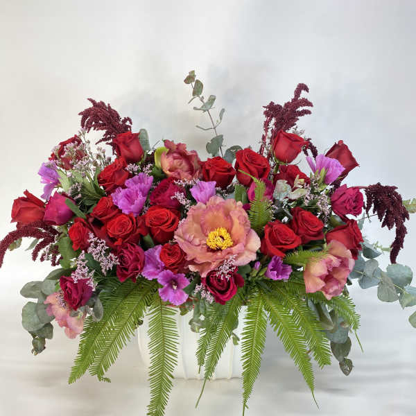 Large mixed bouquet of red roses and pink flowers in a white container