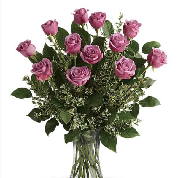 Pink roses arranged in a clear glass vase with mixed greenery