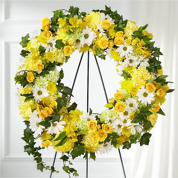 Yellow and white floral wreath with roses, daisies, and mums on a standing easel