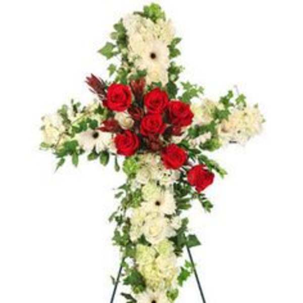 Standing cross-shaped spray of white flowers with red roses on a metal easel