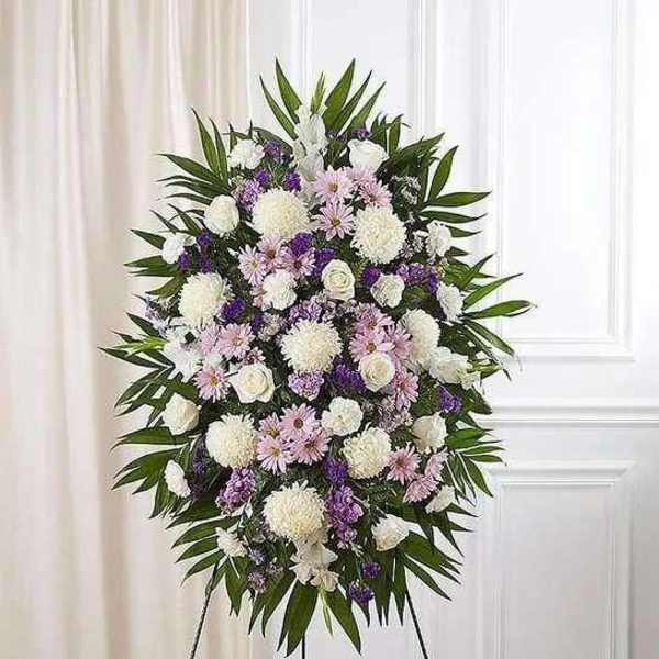 Standing funeral spray with white, pink, and purple flowers on an easel